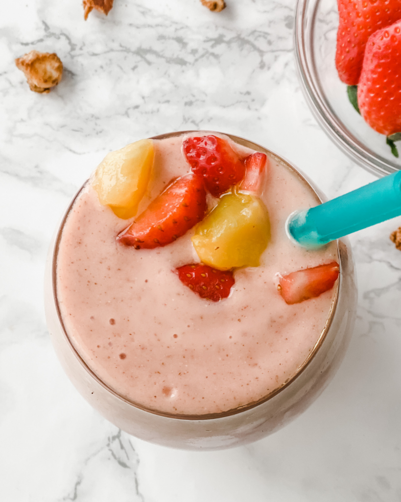 Une photo d'un smoothie aux fraises et à la mangue du haut d'un verre